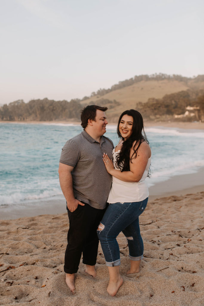 couple posing on the beach for their engagement photos in big sur california