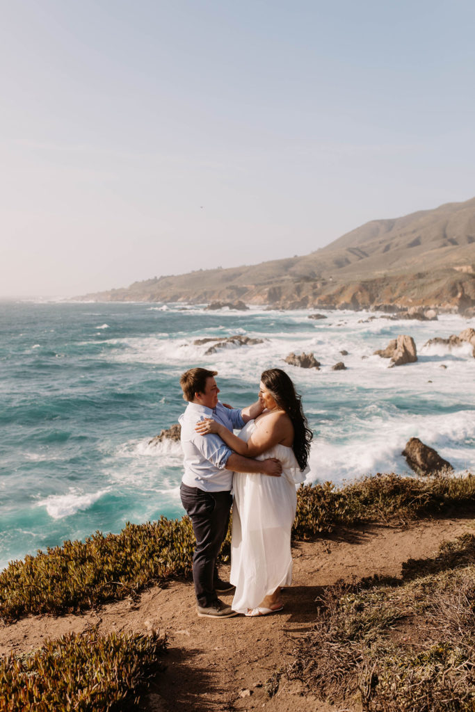 couple posing on the beach for their engagement photos in big sur california