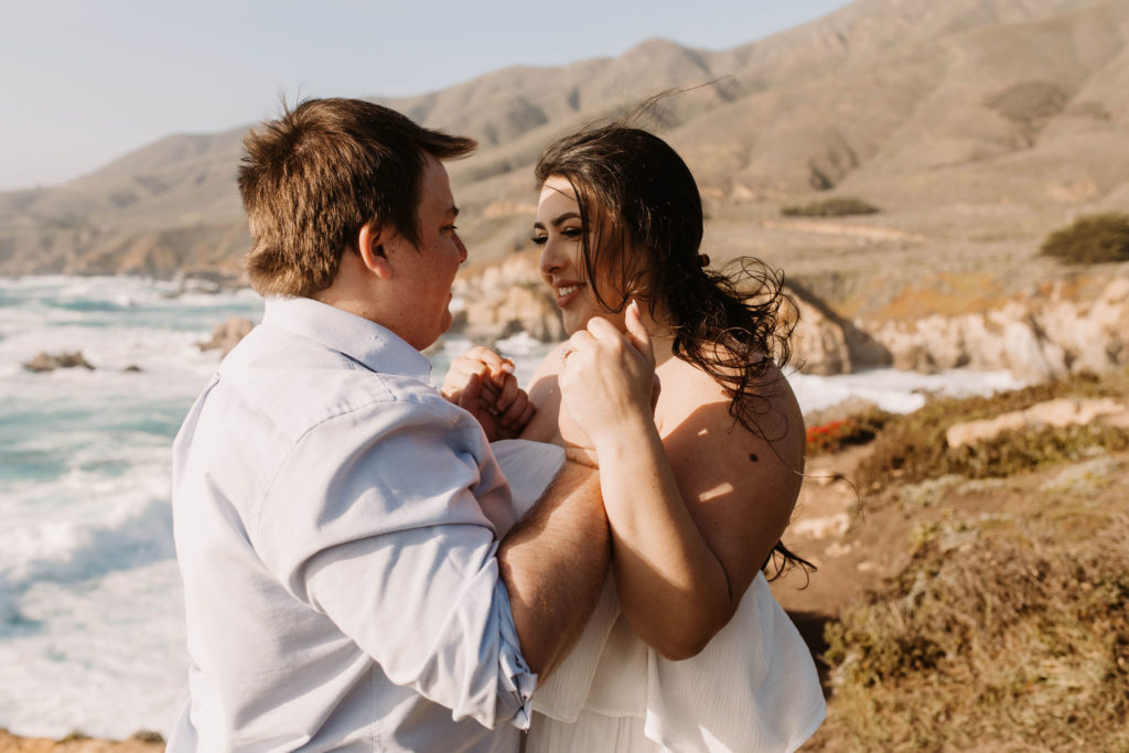 couple posing on the beach for their engagement photos in big sur california