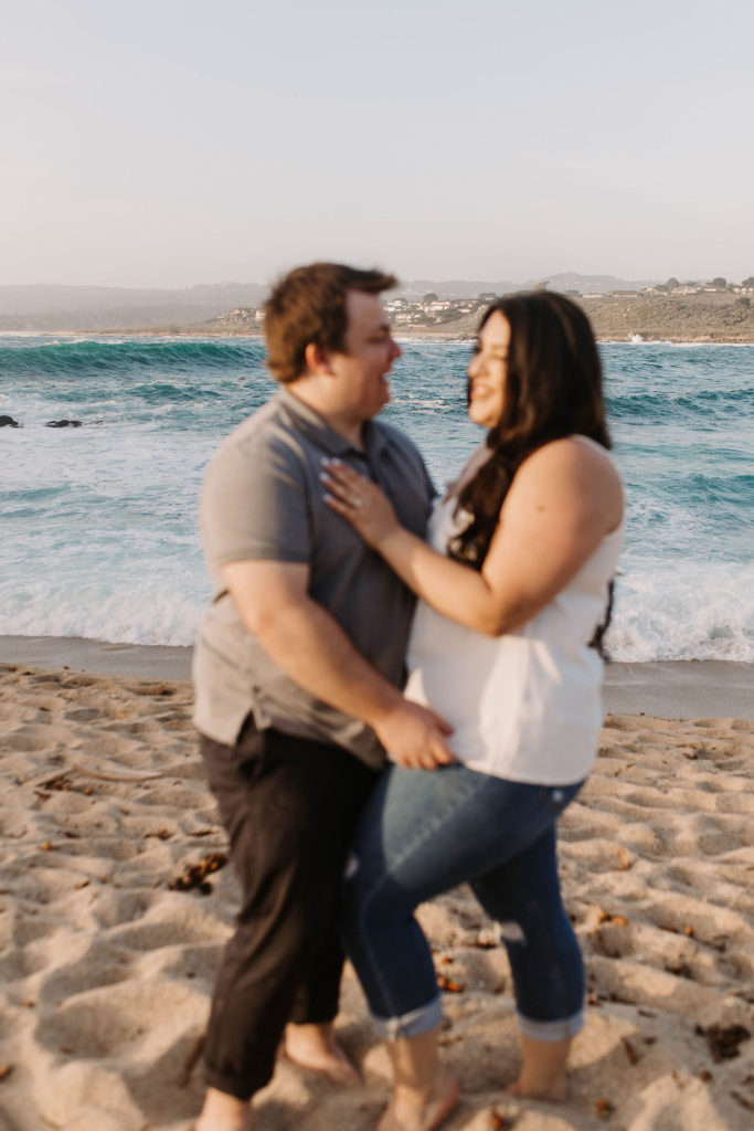 couple posing on the beach for their engagement photos in big sur california