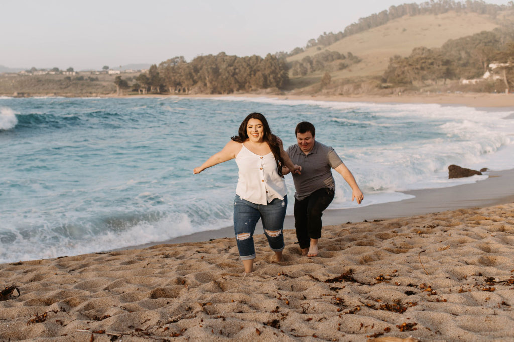 couple posing on the beach for their engagement photos in big sur california