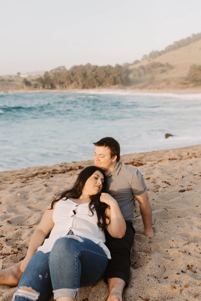 couple posing on the beach for their engagement photos in big sur california