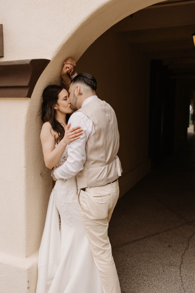 bride and groom posing under an arch