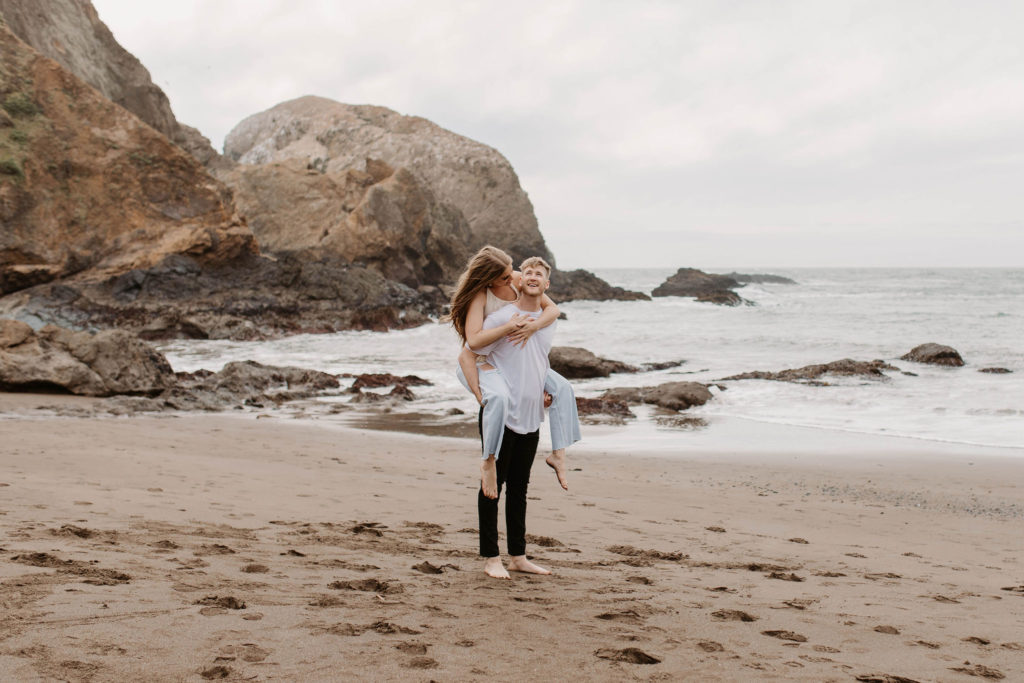 Couple being playful during couples session on the San Francisco beach