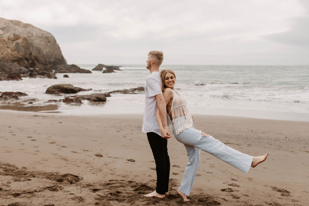 Couple being playful during couples session on the San Francisco beach