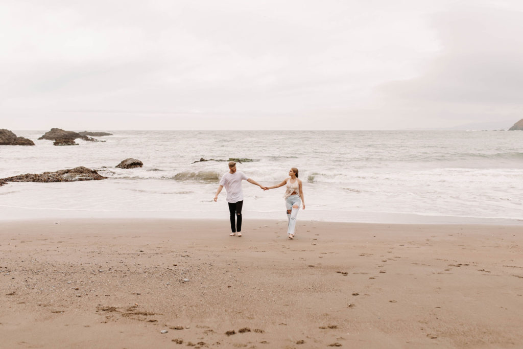 Couple being playful during couples session on the San Francisco beach