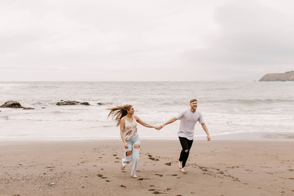 Couple being playful during couples session on the San Francisco beach