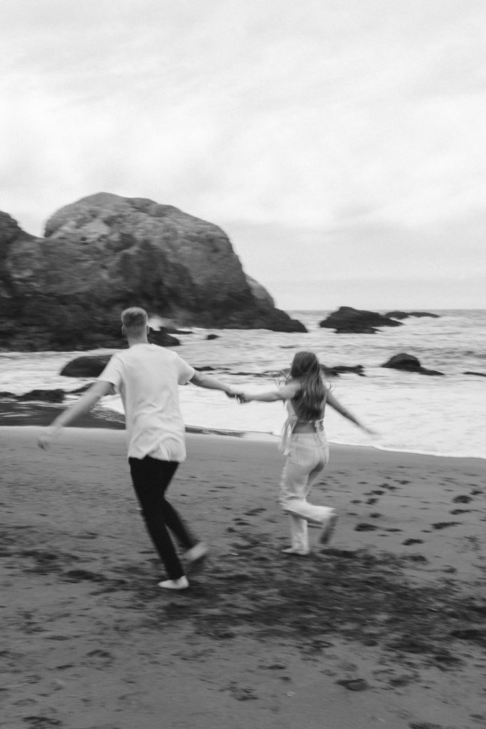 Couple running for photo shoot couple ideas and prompts on beach in San Francisco California