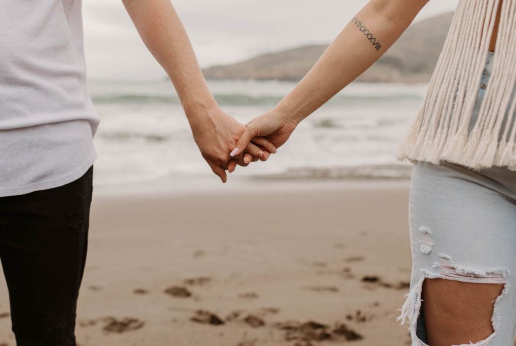 Couple being playful during couples session on the San Francisco beach