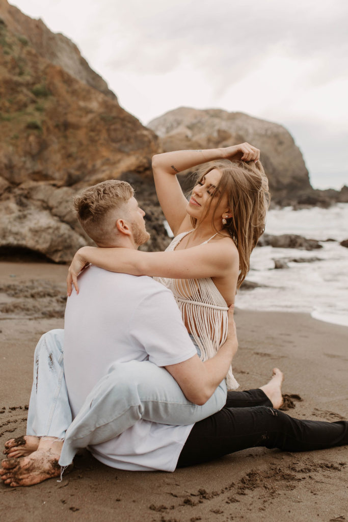 Couple being playful during couples session on the San Francisco beach