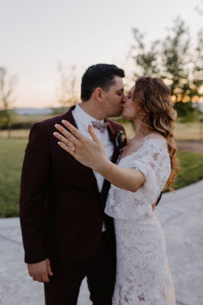 Bride and groom kissing and showing off wedding ring