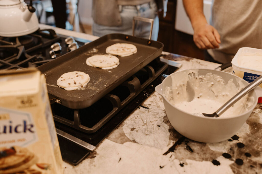 Couple making pancakes during in home couples session - Fun Couples Photoshoot Ideas